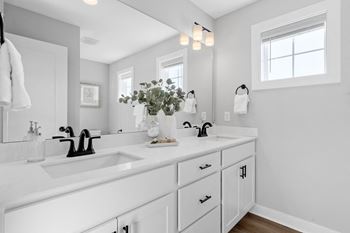 a white bathroom with two sinks and a mirror